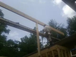 Carpenter setting a ridge beam over a new addition frame — Ice Dam Removal by Roofing Brothers in Locust Hill