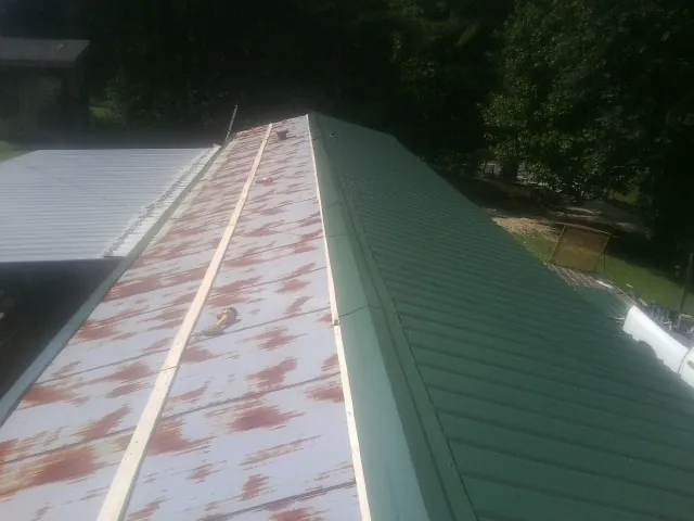Old rusted panels beside newly installed green metal roofing — Wind Damage Roof Repair by Roofing Brothers in Locust Hill