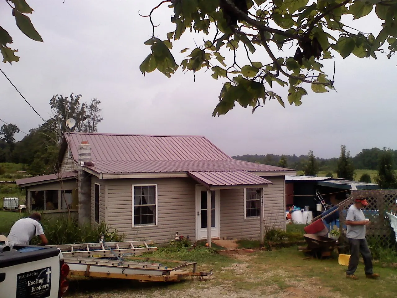Crew finishing a mauve metal roof on a small farmhouse in Locust Hill