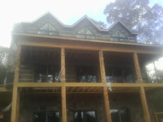 Dormers and porch framing on a large log home under construction — Roof Coating work by our crew in Locust Hill