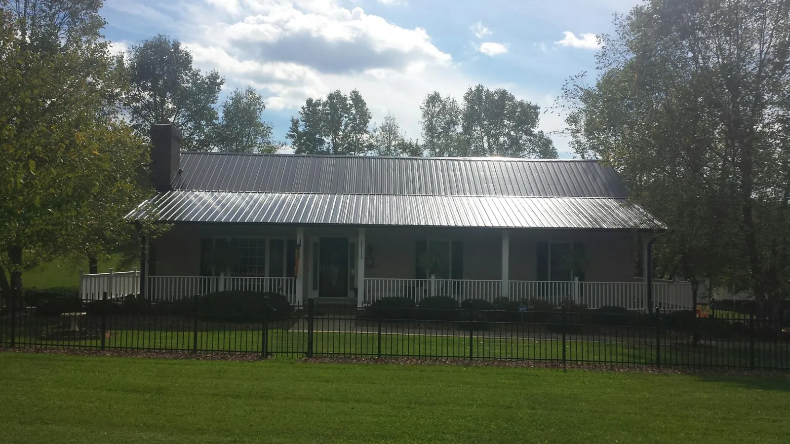 Gray metal roof on a brick ranch with a full width front porch — Gutter Guard Installation work by our crew in Locust Hill