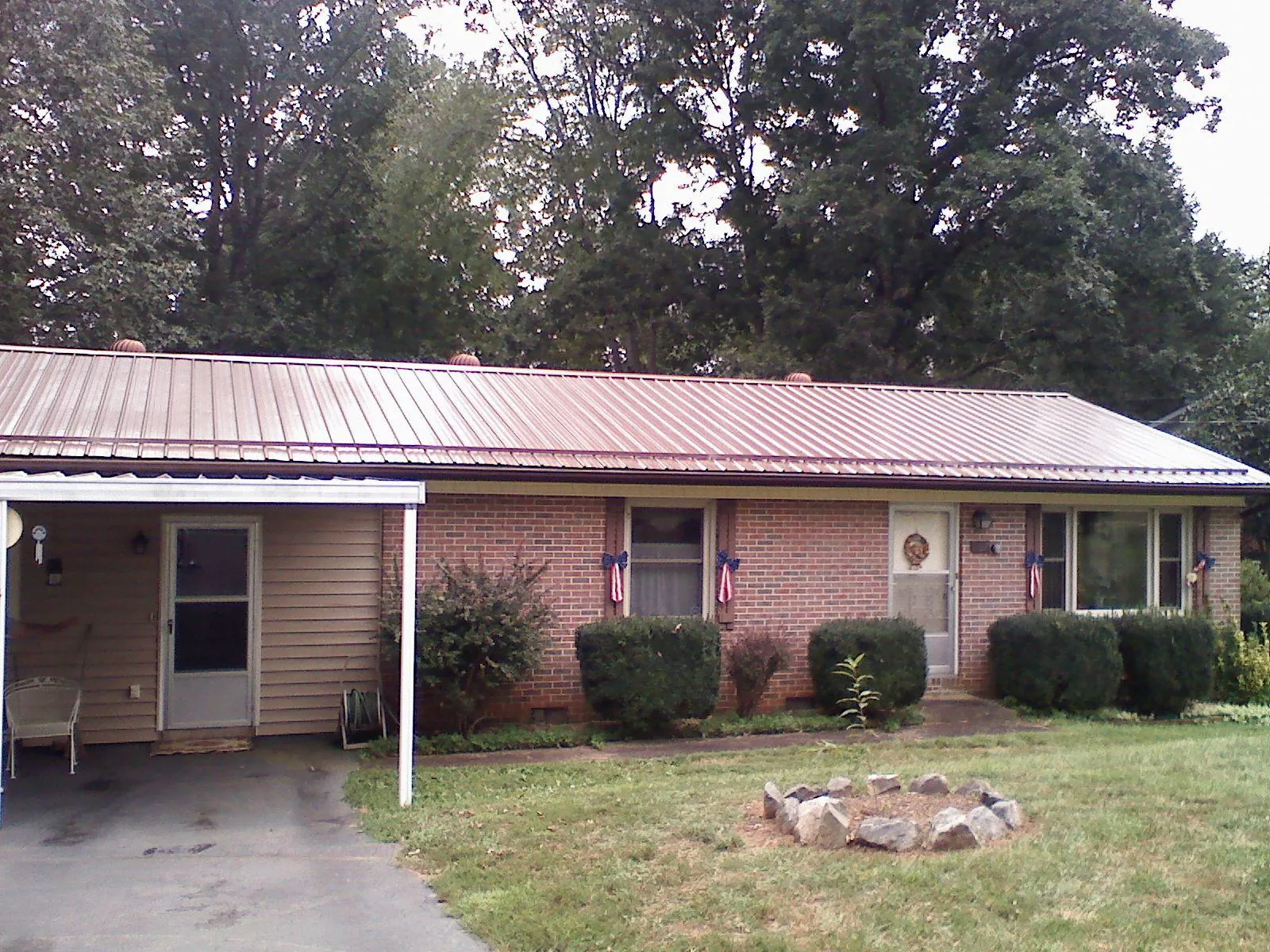 Bronze metal roof and carport on a brick ranch home — Roof Repair work by our crew in Locust Hill