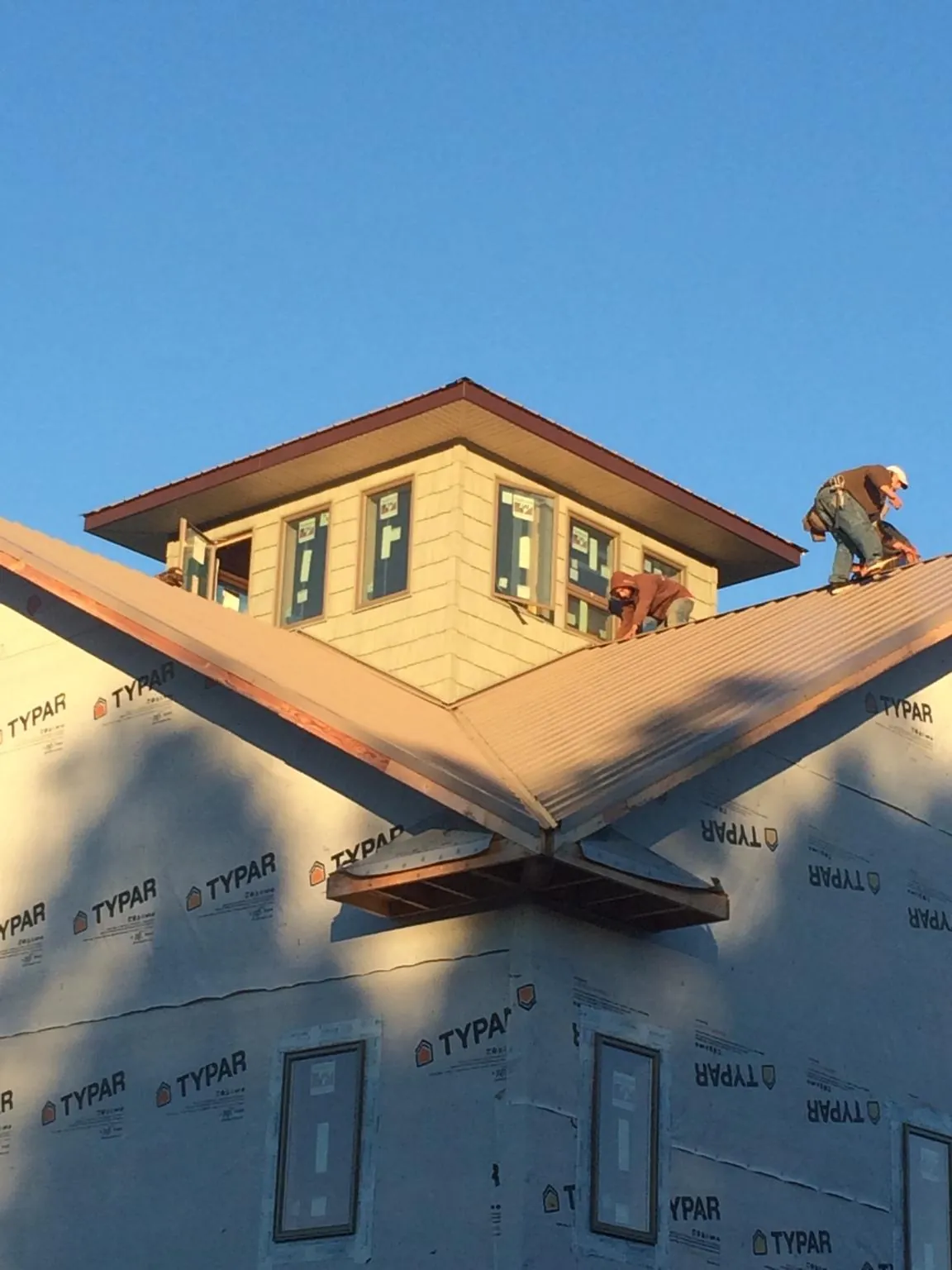 Roofers working around a rooftop cupola on a new metal roof at sunset — Roof Waterproofing in Locust Hill by Roofing Brothers